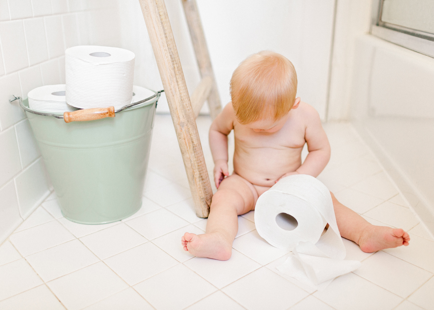baby-boy-plays-with-toilet-paper-in-bathroom